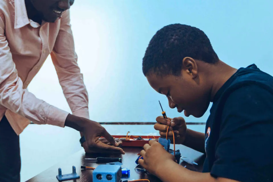 A mentor helping a young maker with an electronics build