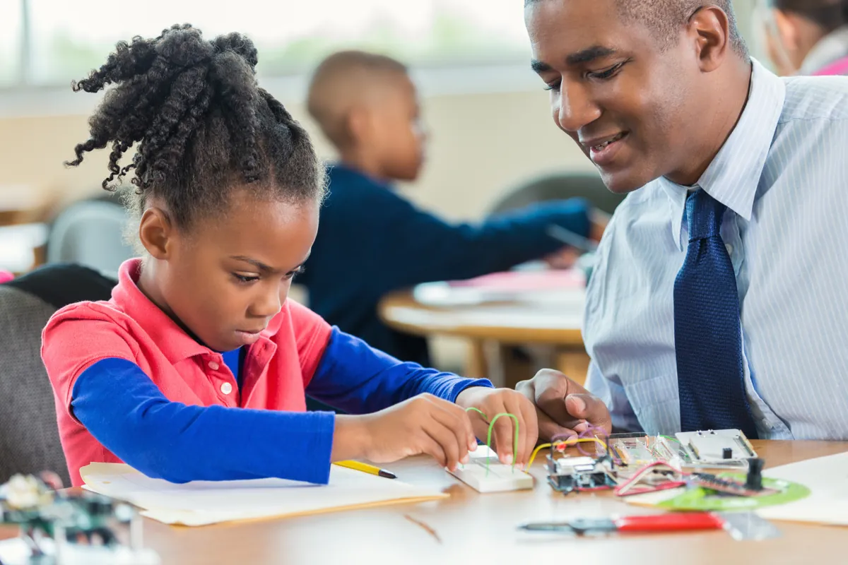 A child in South Africa wiring an Arduino board and breadboard at a desk